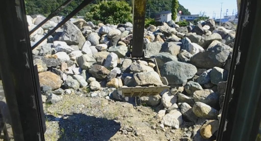 ユンボのバケットに小さい石を詰め込んで、トラックの荷台にあけます。