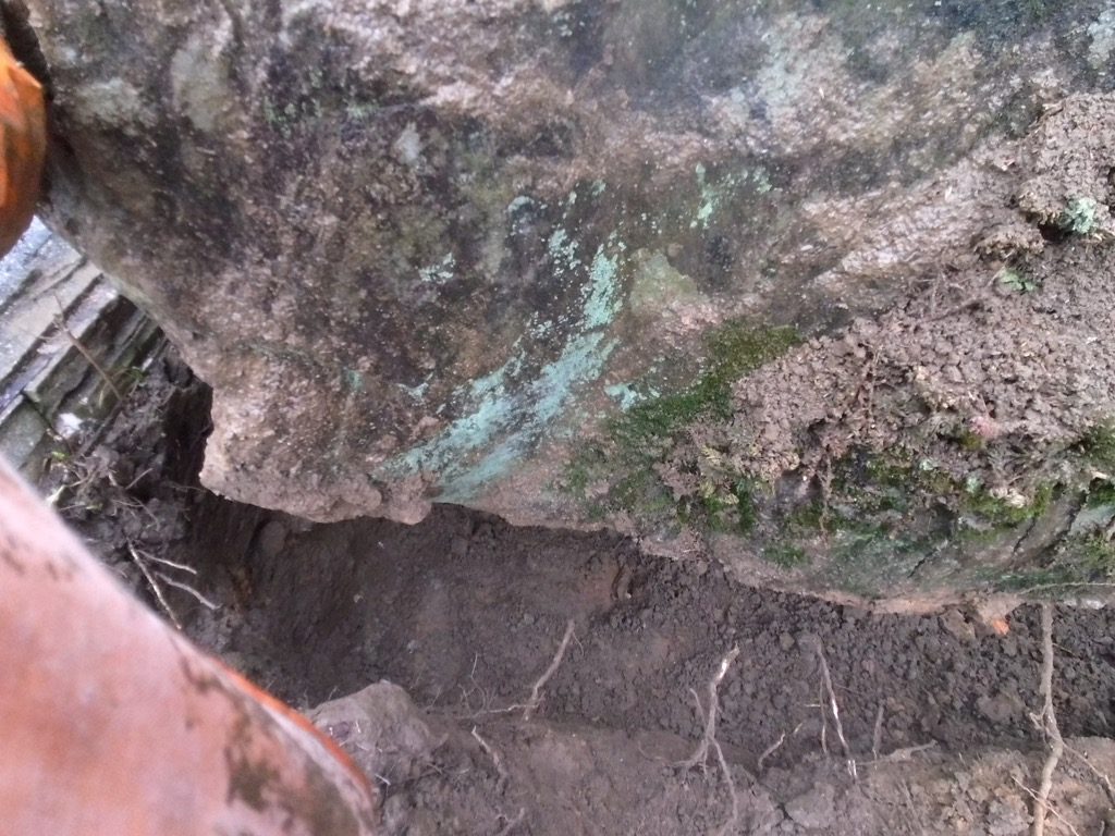 ワイヤーを通して吊り上げるため、石の下側を人力で掘っています