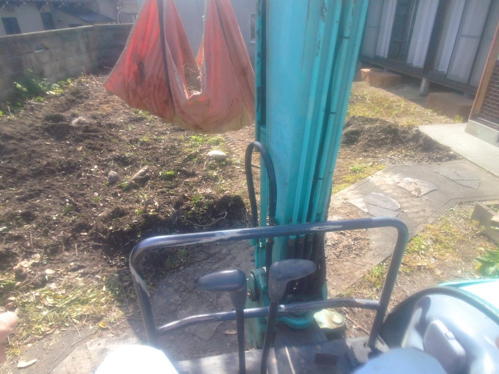 布モッコに入れたゴミをユンボで吊り上げる