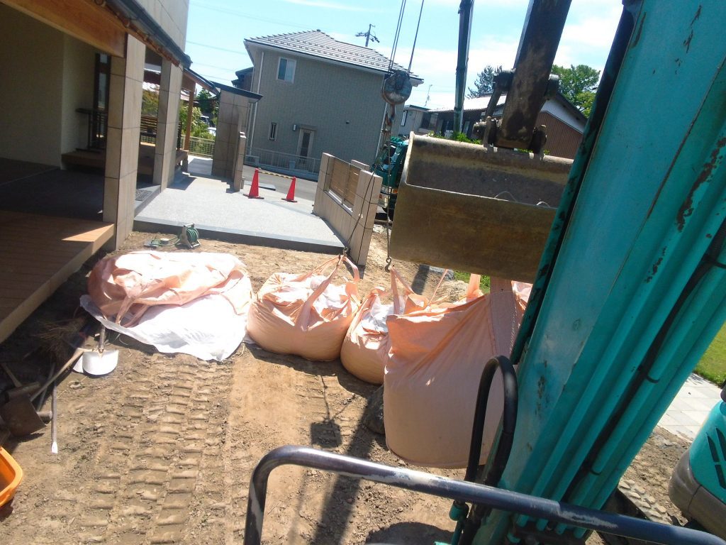 フレコンに入った揖斐砂利を、ユンボで運びます。約10t分を家周りに敷き詰めるので、人力では、ちょっとしんどい。