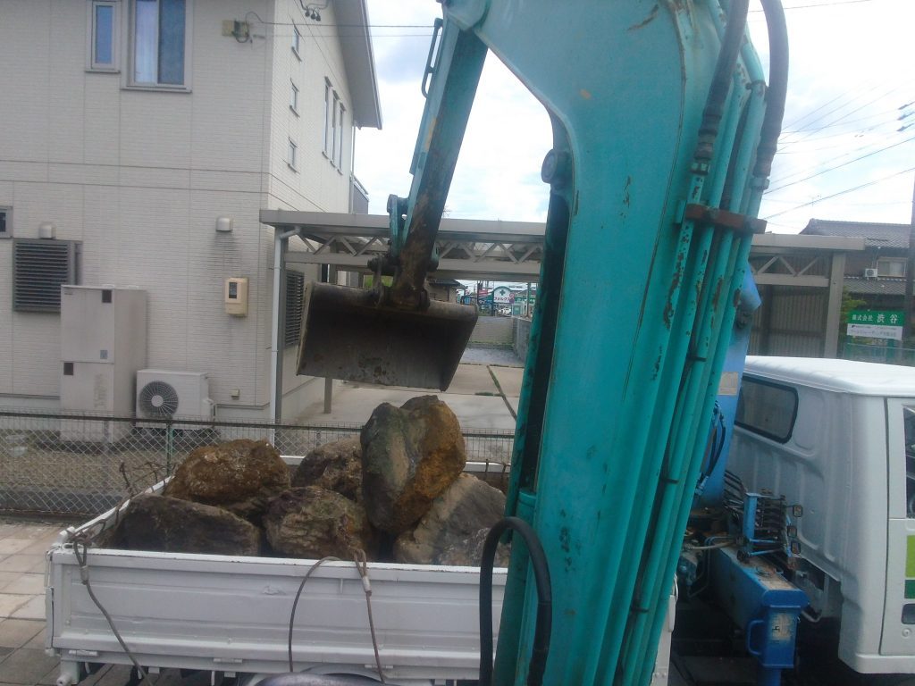 庭石をユンボですくって、トラックに積み込んでいます
